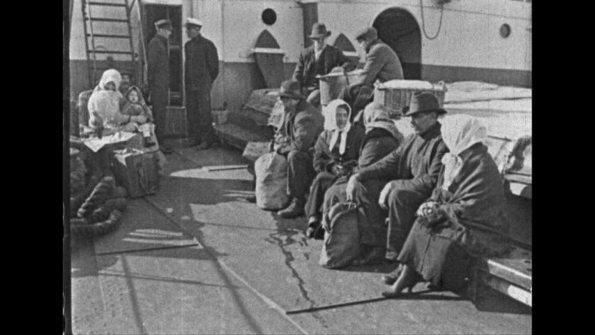 1930s: UNITED STATES: immigrants on deck of ship. People board ship. Lady puts down basket