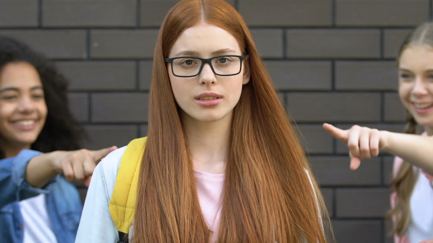 Teenagers pointing at red hair girl in glasses, mocking nerd, verbal bullying | Shutterstock HD Video #1033504775