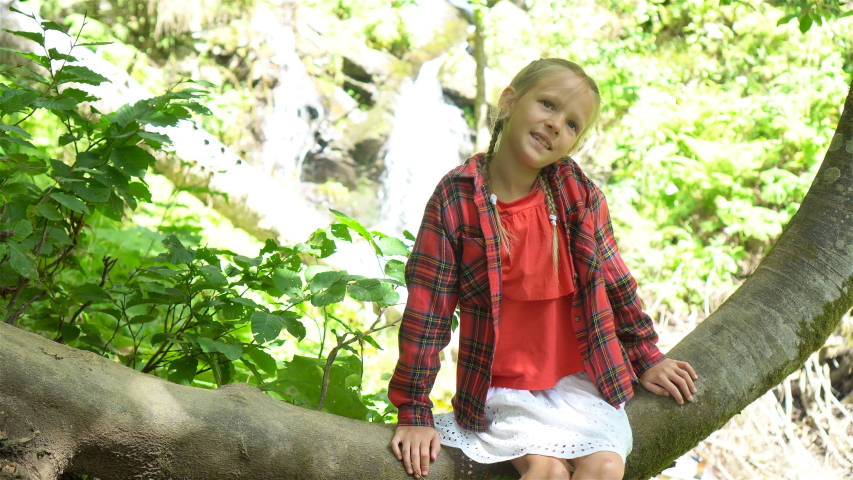 Little kid girl smile with fun and enjoy water splash on waterfall and holiday relax summer trip