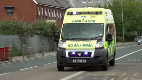 UK Ambulance vehicle responding to emergency, siren and blue flashing lights. Driving in city, town, street, road.  Filmed Kingston upon Hull city centre 18/07/2019