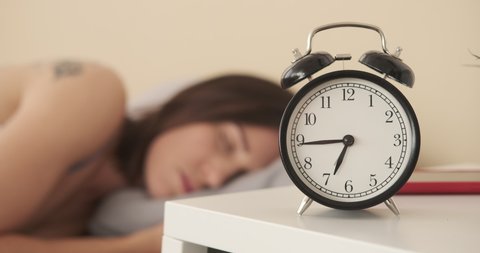 Woman turning alarm clock off in the morning