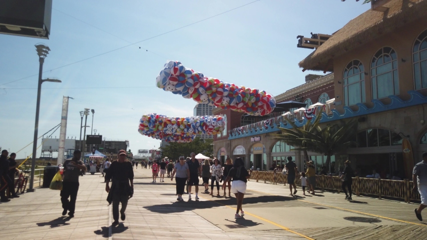 Atlantic City, New Jersey - May 24, 2019: Tourists walking and dancing along the Atlantic City boardwalk in front of the casinos on a sunny summer day