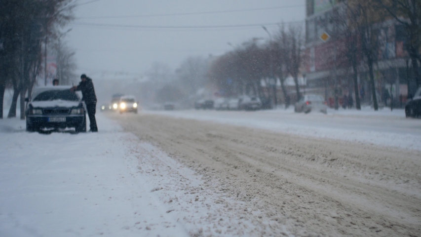 Car urban traffic in the heavy snowstorm blizzard snowfall on the snowy road in the winter city 