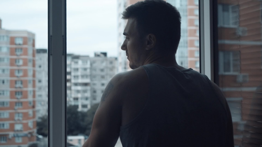 A man stands near the open window and looks at the city. Outside the multi-storey building. The concept of freedom and pleasure. Royalty-Free Stock Footage #1033524077