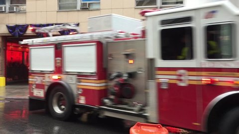 NEW YORK CITY - JULY 21, 2019: FDNY firefighters firemen and Fire trucks pull out of fire station in lower Manhattan with sirens and lights on to fight fire.