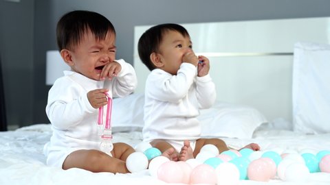 twin babies crying on a bed