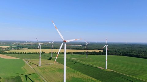 Aerial drone view of five wind power turbines, part of a wind farm, on a green field in eastern Germany near the city of Cottbus, Brandenburg. Wind turbines are part of the energy transition strategy.