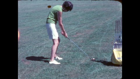 1960s: Golf course. Woman in white shorts swings at ball, it falls and rolls forward. She takes a second swing, hits it down the course, looks back at the camera.