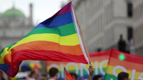 A LGBT gay pride rainbow flag being waved at a pride march celebration event