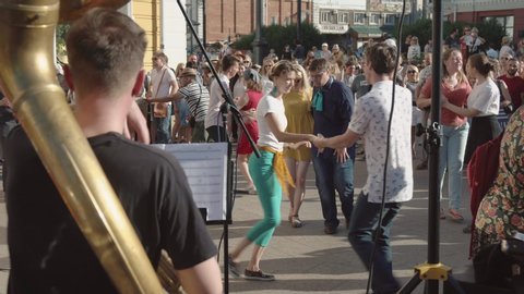 Omsk, Russia - July 13, 2019: People listen to music, have fun and dance in the city street to the music of a brass band.