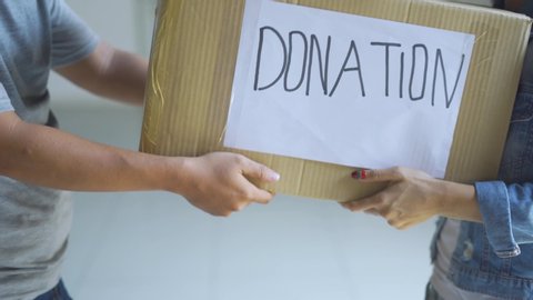 Donation concept. Man giving a donation cardboard box on a woman. Shot in 4k resolution