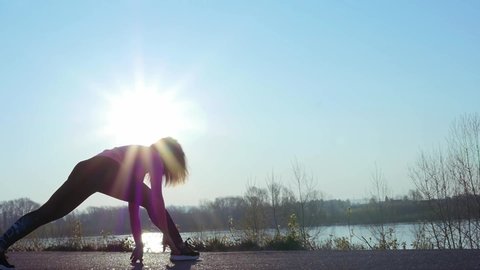 athletic woman goes in for sports on the river bank at sunrise. slow motion