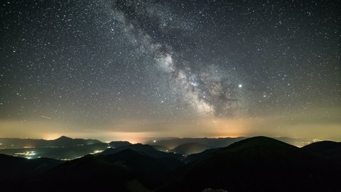 Starry night in mountains Time lapse. Milky way galaxy stars moving over countryside traffic. Night to day