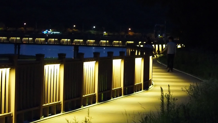 wooden deck with fence in lake side for walkway, there are many lighting