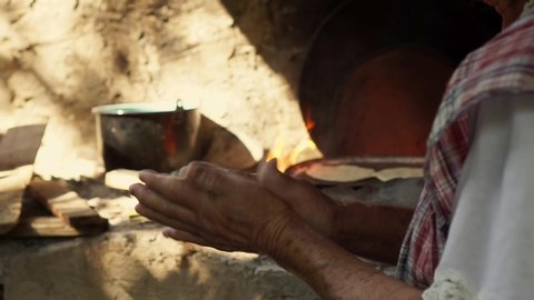 Mexican woman from Cuetzalan making authentic tortillas by hand in a typical “Comal” pan.