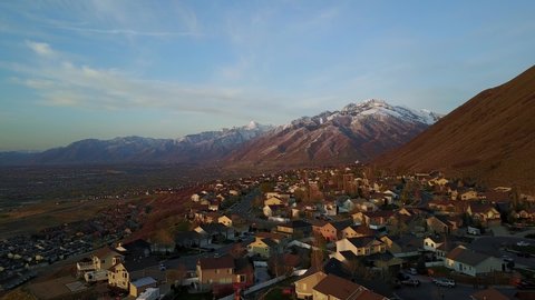 Drone Shot flying over a neighborhood in Draper City, Utah during sunset hours. The Wasatch Mountain range can be seen in the distance with part of the Salt Lake Valley showing as well.