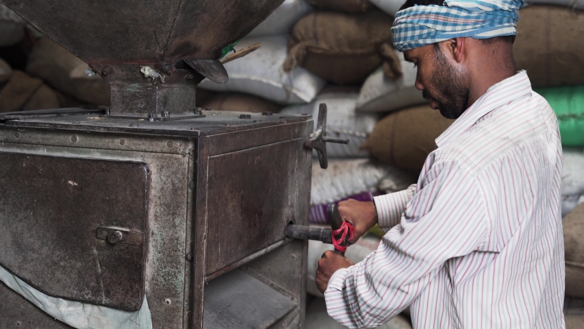 Worker in white shirt working with rice mill machine