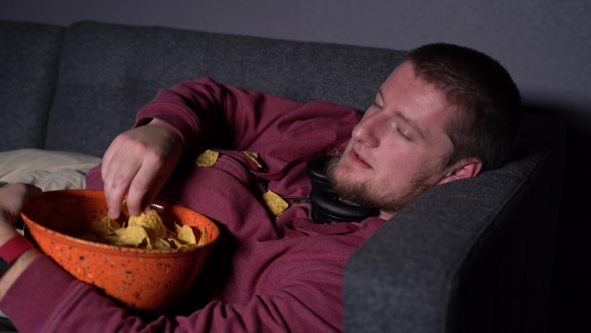 Caucasian Male Lying on a Sofa and being Lazy Watching TV | Shutterstock HD Video #1033622660