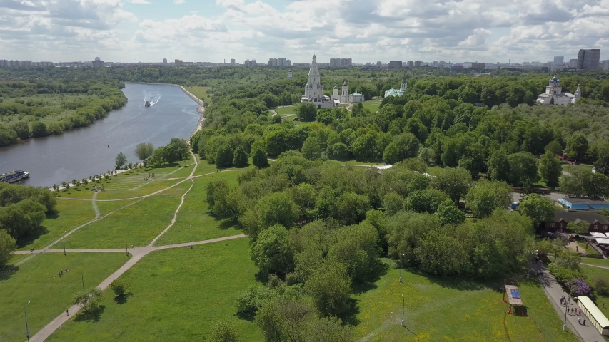 Flying over green areas of Kolomenskoye on the bank of Moskva River with sailing boats. Scene with Church of the Ascension. Moscow, Russia