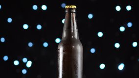 Beer bottle close-up. Dark beer in bottle rotated over black background. Bottle of beer turns slowly around its axis. 4K video. Black background.