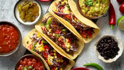 Tasty Mexican meat tacos served with various vegetables and salsa. With sides in ceramic bowls around. Top view composition.