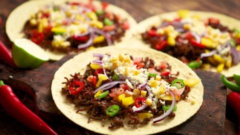 Healthy corn tortillas with grilled beef, fresh hot peppers, cheese, tomatoes over rusty wooden table background, top view, copy space. Mexican food contept.