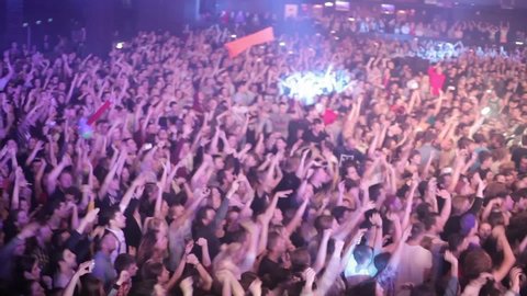 Concert crowd waving hands on dance floor in music hall.Festival crowd partying to music of famous rap singer,video clip filmed in night club.Editorial footage from live event.MOSCOW-7 DECEMBER,2015