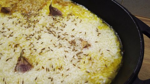 Cooking of boiling traditional asian pilau with lamb meat, garlic and rice. 4K clip