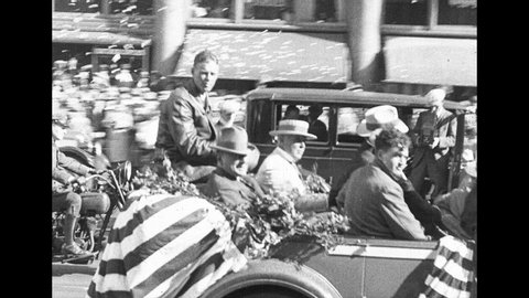 1920s: Charles Lindbergh rides in back of convertible car down street in parade.