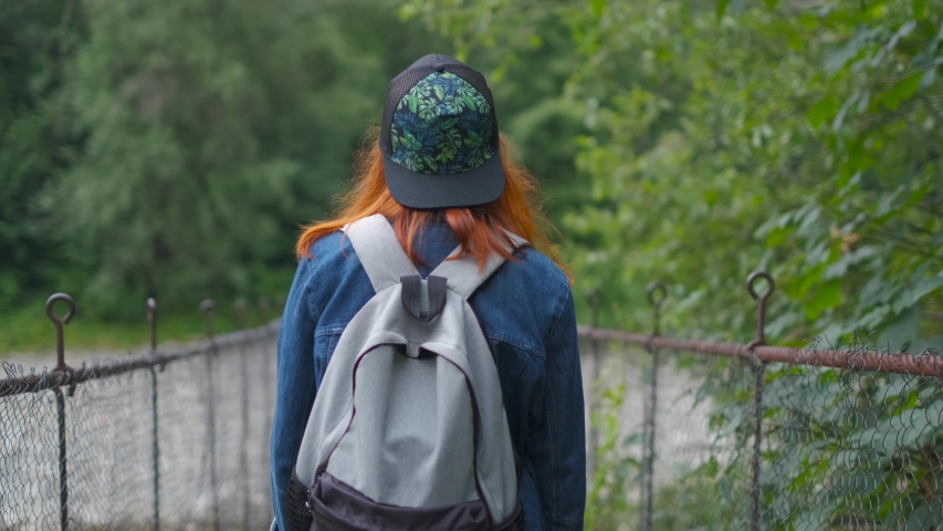 Young girl walks on the suspension bridge