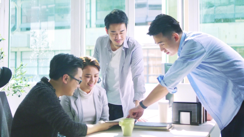 Group of four young asian business people men and woman meeting discussing in office