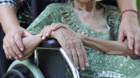 Daughter takes care elderly mother in wheelchair at home