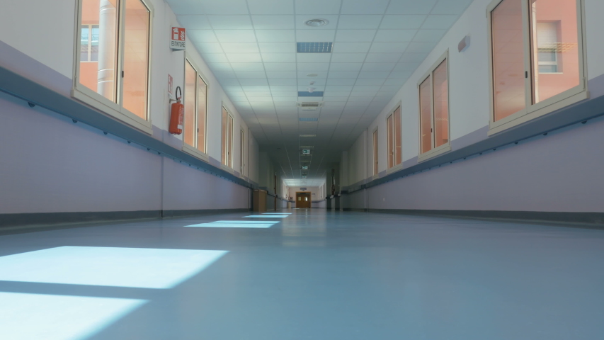 Beginning of the work day. Doctor on the move puts on a white uniform in a hurry and walks down the hospital corridor. Medical worker goes along the corridor of a large modern hospital. Royalty-Free Stock Footage #1033696133
