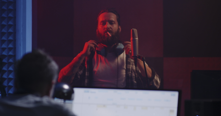 Medium shot of vocalist lighting cigarette in sound booth