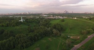 4K quality aerial video scenic view of beautiful light blue church overlooking green park, distant city and hills in Krylatskoye area on quiet cloudy afternoon near Moscow River in Moscow, Russia