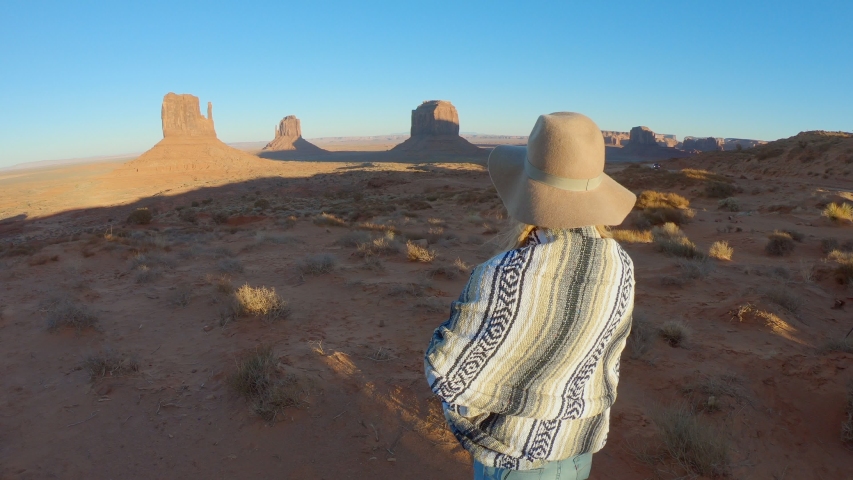Woman rising arms at sunrise in the morning embracing travel in USA at Monument Valley; Girl in the American desert arms wide open embracing nature 