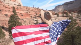 Girl traveling in USA holding American flag in the air, nature landscape in Zion national park- Young woman celebrating America- Slow motion video 