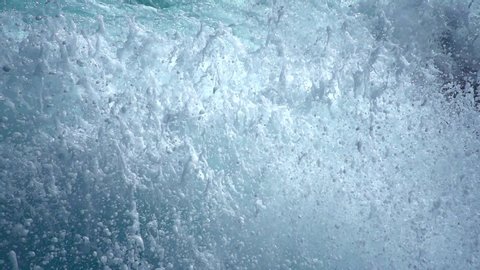 Sea tide waves caused by propeller engines churn water waves and wake up. Splashes of blue water in the open sea. Close-up. Boiling water in reverse. Fresh breeze