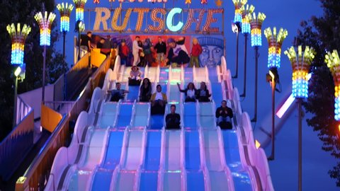 Düsseldorf, Germany - JULY 2019: Friend enjoy and slide from the top of " Super RUTSCHE" means slider, playful, illuminate and night atmosphere of Rheinkirmes, annual amusement park in summer season.