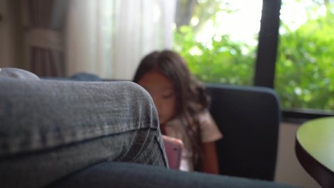 Asian kid girl sitting relax and using tablet computer at home, slow-motion handheld  panning shot