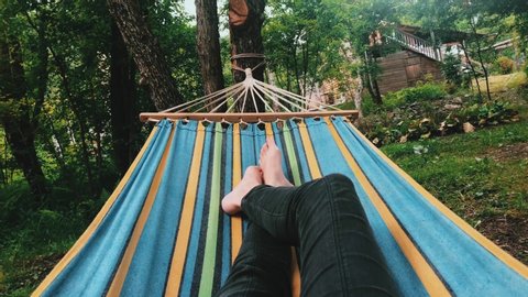 Video from the first person. Relaxed female legs swinging in a hammock. Nature and man together on 4k video.