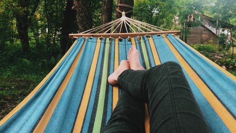 Video from the first person. Relaxed female legs swinging in a hammock. Nature and man together on 4k video.