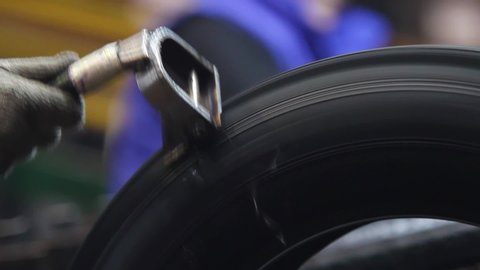 Tool for stripping tires after molding. Tire handling at the factory from excess rubber. Car tiyes production. Detailed production process of car tires, closeup. Rotation of the wheel close up.