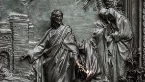 Beautiful Duomo di Milano iron gates decor in close up.Jesus Christ & other figures in exterior design of ancient catholic church in center of Milan city in Italy.Gothic architecture style in details