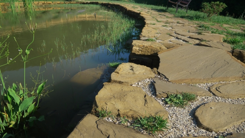 landscape design concept. stone paved path along the pond