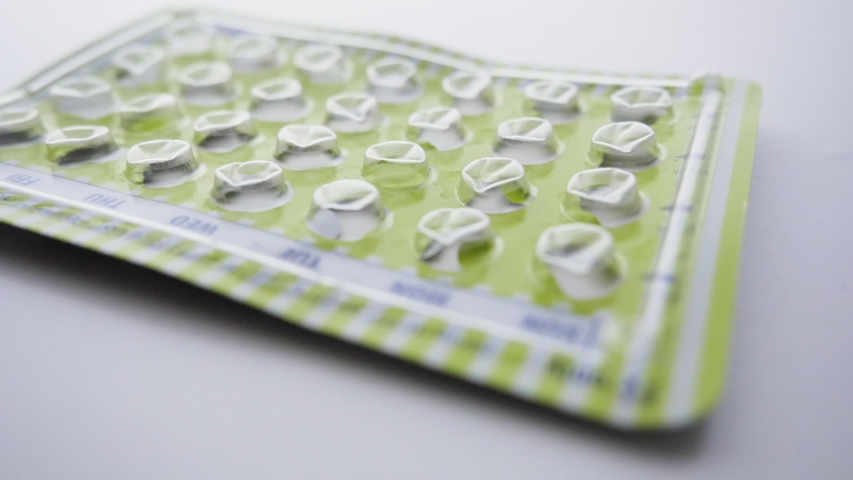 Empty package of birth control pills drops. Oral contraceptives prevent unwanted pregnancy and are the lynchpin of women's reproductive rights. | Shutterstock HD Video #1033748222