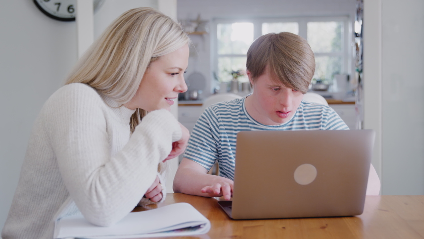 Downs Syndrome Man Sitting With Female Home Tutor Using Laptop For Lesson At Home Royalty-Free Stock Footage #1033763873