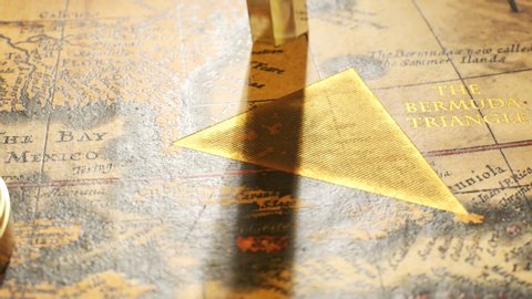 Famous Bermuda triangle marked with golden ink on an old, vintage map. A sign marks the spot of mysterious disappearing and ship disasters. Retro compass malfunctioning, can't find the right direction