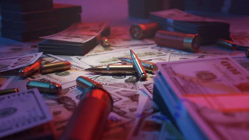 Shiny, brand new ammo bullets in the middle of mafia table. A lot of dollar bills stacked on top of it  Gangster crime wealth and deadly force. Neon red and blue lights illuminating the cash. 4KHD
