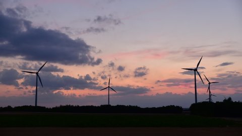 Wind turbines for green energy generation in fast motion at dusk in Parndorf, Burgenland.